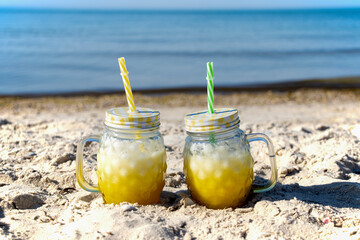 A yellow cocktail in a copper mug stands on the seashore. Sunny day, golden sand and a cooling drink. Yummy.