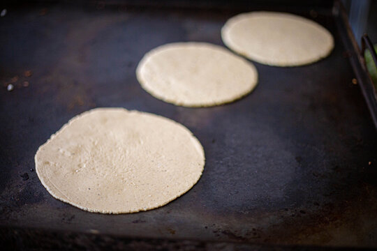 comal metálico muy caliente cocinando unas tortillas de maíz típicas de  guanacaste costa rica, en una estufa de acero a la leña foto de Stock