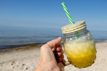 I am holding a yellow cocktail in a fashionable mug in my hand. Summer vacation. Healthy lifestyle. Smoothie