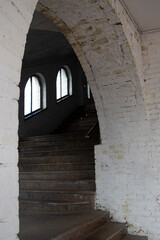Arches in the white brick wall, shadows on the floor, a passage down the stairs