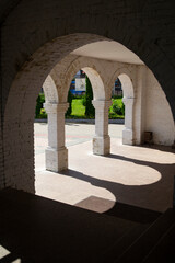 Arches in the white brick wall, shadows on the floor, a passage down the stairs