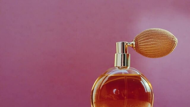 Luxury golden perfume bottle and shining light flares on pink background, glamorous fragrance scent as perfumery product for cosmetic and beauty brand, stock footage