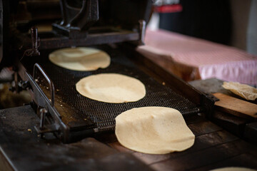 Maquina de tortillas preparando la masa para que salgan hechas, hechas en mexico, tradiciones