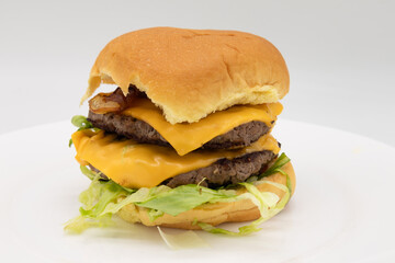American Double Cheeseburger with Bacon and Lettuce on a White Plate