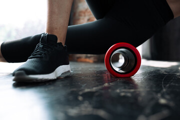 Close-up of legs of young woman doing a warm-up exercise using a fascia massager to warm up the...