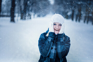 Fototapeta na wymiar Winter girl smiling happy having fun outdoors on snowing winter day. Cute playful young woman winter outdoor during snowing.