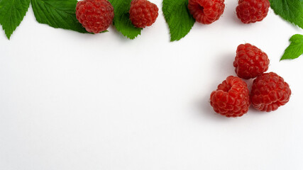 Ripe raspberries isolated on white background close-up. Beautiful red fresh raspberries with leaves along the contour on the table. Top view. Banner for the site. Free space for text in the left