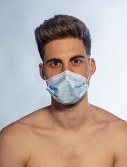Shirtless Caucasian man wearing a medical mask for preventing the spread of COVID-19