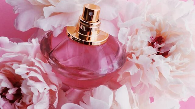 Pink perfume bottle with peony flowers, chic fragrance scent as luxury cosmetic, fashion and beauty product background, stock footage