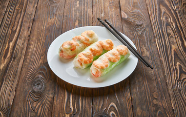 Asian food spring rolls with shrimps on a dark wooden background. Spring rolls in rice paper with a chopsticks. Space for text