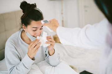 Female getting her fever checked by a nurse with a digital thermometer