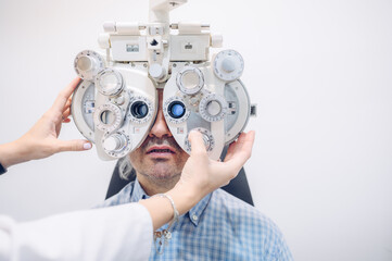 Woman optometrist examining the vision of a middle-aged gray-haired caucasian man
