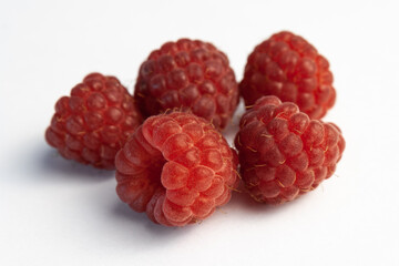Five ripe raspberries isolated on a white background close-up. Fresh raspberries without sheets on the table. Macro shooting. Healthy and wholesome food concept