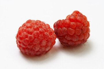 Two ripe raspberries isolated on a white background close-up. Fresh raspberries without sheets on the table. Macro shooting. Healthy, wholesome food