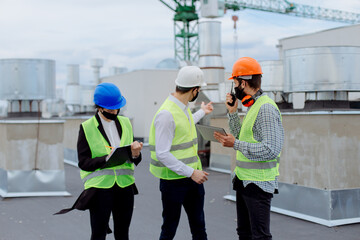 Good looking multiethnic group of workers in a modern building construction site analyzing the plan of construction they wearing the safety helmets