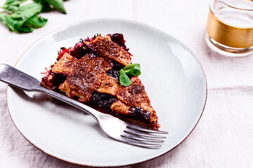 Slice of Delicious Homemade Berries Honeysuckle Pie on beige linen tablecloth. Selective focus