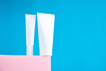 Two white empty tubes for cream on a light blue background. Creative layout.
