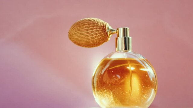 Luxury golden perfume bottle and shining light flares on pink background, glamorous fragrance scent as perfumery product for cosmetic and beauty brand, stock footage
