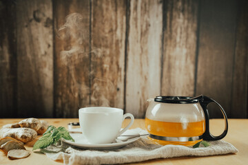 Cup of hot ginger tea with lemon and mint with steam from cup on wooden table. the concept of natural medicine.