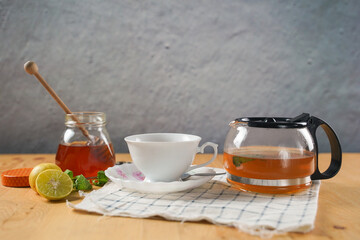 Cup of hot honey lemon tea with mint with steam from cup on wooden table over black background. the concept of natural medicine.