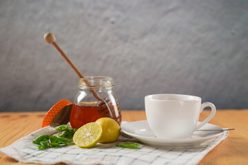 Cup of hot honey lemon tea with mint with steam from cup on wooden table over black background. the concept of natural medicine.