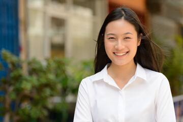 Portrait of young beautiful Asian businesswoman outdoors
