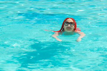 Fototapeta na wymiar A woman with African pigtails swims in the pool.