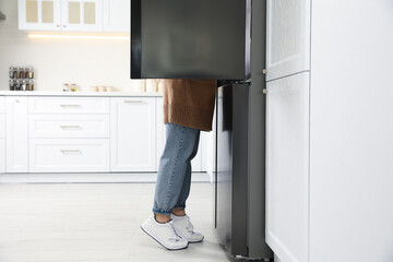 Young woman looking into refrigerator in kitchen