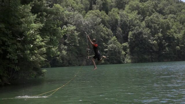 Young Boy On Rope Swing Over Lake In Slow Motion 