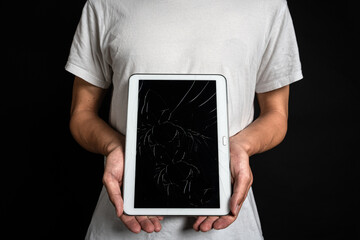 画面にヒビの入ったタブレットをもつ人 © HI