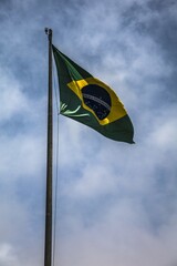 Vertical low angle shot of the waving flag of Brazil under the dark cloudy sky