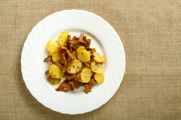 Plate with fried potatoes with mushrooms larvae on a linen tablecloth copy space