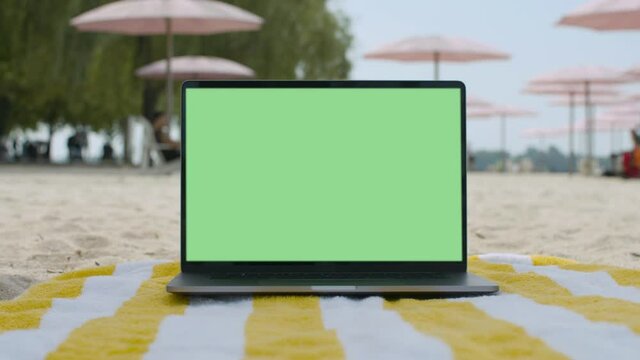 Remote work lifestyle. Working from the beach. Green screen laptop computer sitting on beach blanket.4K and HD. Download the preview for free.
