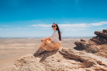 Beautiful woman in a dress on the mountain. The girl at the top of the mountain looks into the distance.