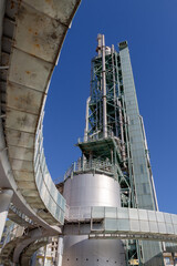 Obraz premium A bottom-up wide-angle view of an abandoned old refinery tower made of steel with its round ramp framing the image in a sunny day with a blue sky in Lisbon, Portugal.