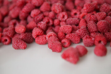 a lot of raspberries on a white background, close-up, red, ripe, free space, place for an...