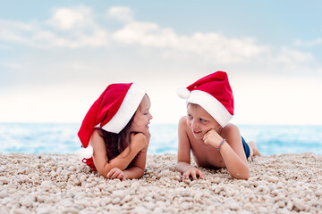 Siblings with Santa hats on the beach