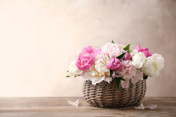 Fototapeta na wymiar Beautiful peony bouquet in wicker basket on wooden table. Space for text