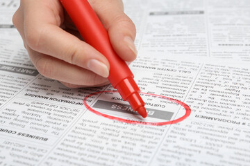 Obraz premium Woman marking advertisement in newspaper, closeup. Job search concept