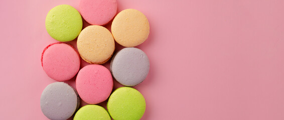 Pile of colorful macaroon cookies on pink background