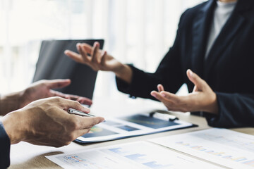Young man in a black suit is analyzing financial graphs with a black woman in the office.
