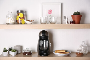 Modern coffeemaker on wooden table near white wall