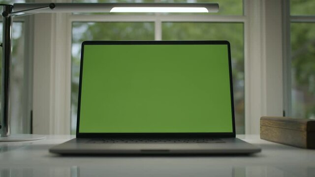Working from home. Green screen laptop computer sitting on a home work desk next to a desk lamp. Footage shot with RED, available in 4K and HD. Download the preview for free.
