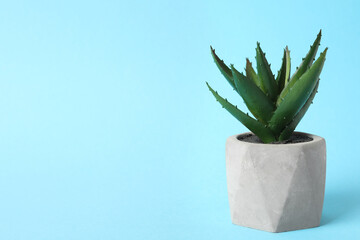 Beautiful artificial plant in flower pot on light blue background, space for text