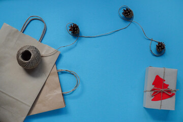 Christmas layout on blue background, top view. Flatley, Packed in craft paper with red christmas tree tied with string. cones create comfort in cold, decor. New year holiday concept with copy space
