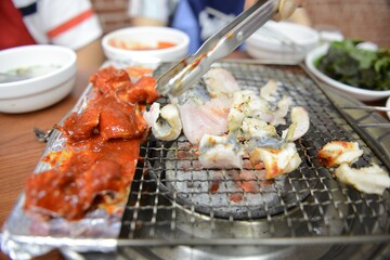 Closeup of seafood on a metallic tray on fire in Jagalchi Market, Busan, South Korea