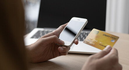 Asian man is holding a credit card and paying with a mobile phone.
