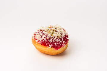 A donut coated with strawberry syrup and garnished with coconut and slices of candied fruit