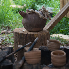 A steaming teapot and tea cups. Tea preparation in a clay pot on a fire. A camping trip, a journey.