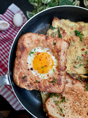 Egg in a hole and Egg sandwiches on a pan with herbs and chili flakes
